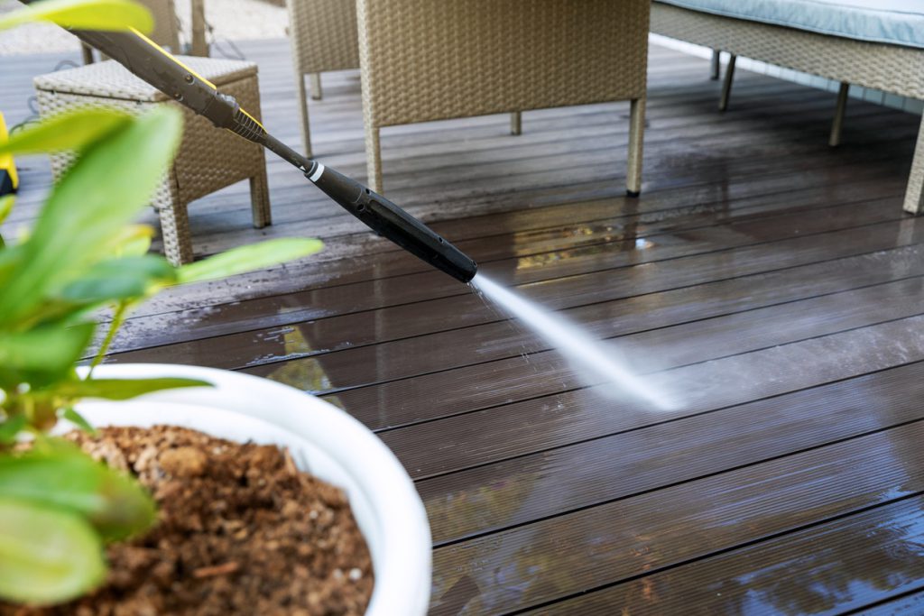 Worker power washing wooden deck