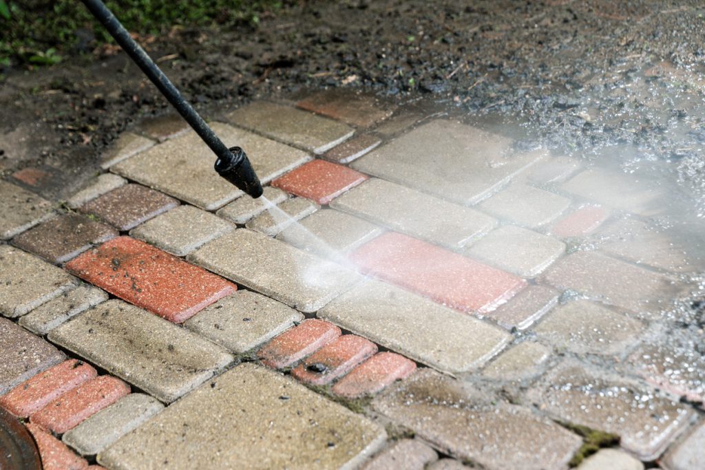 Power washing dirty brick pavement