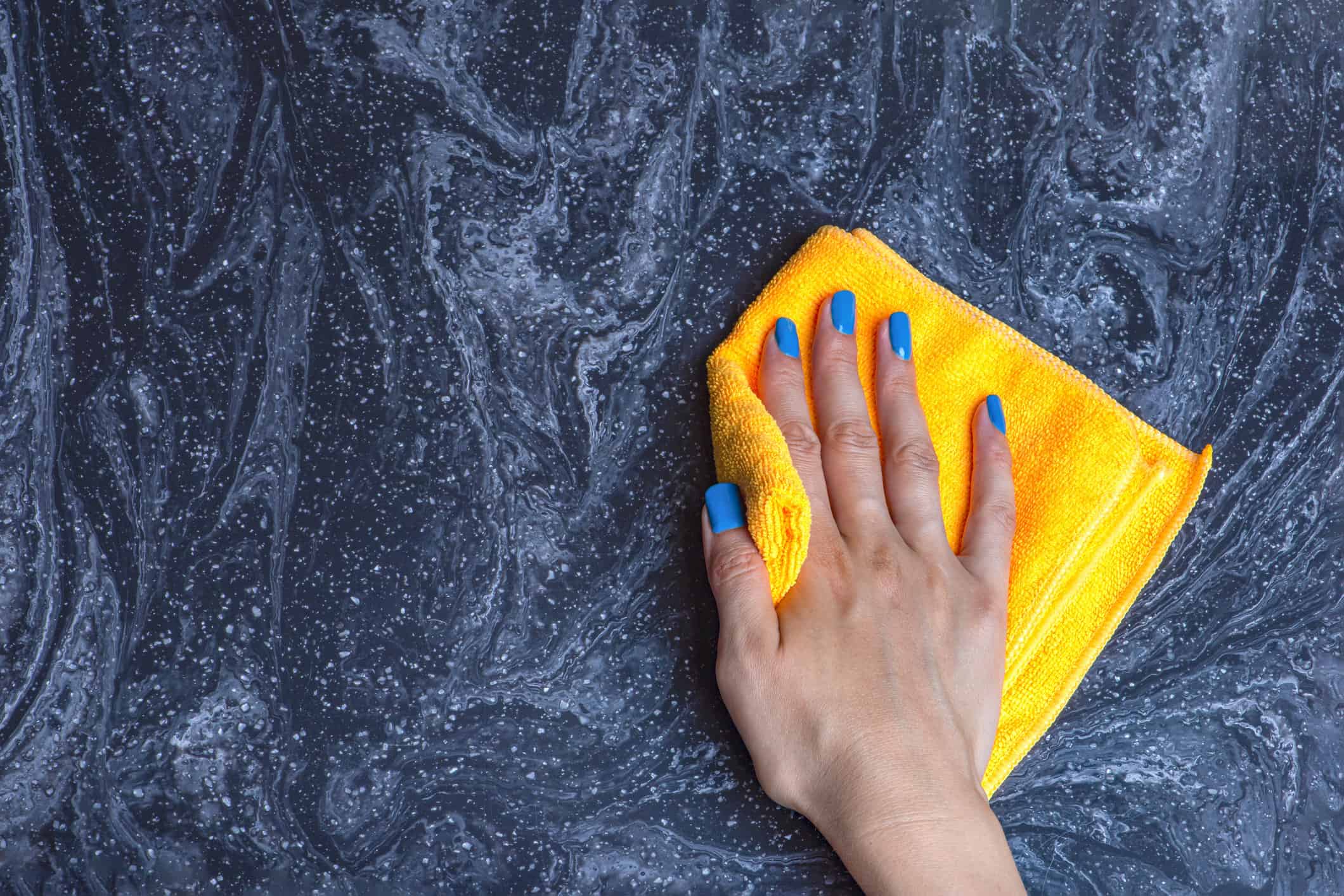 Lady with blue nails cleaning the countertop