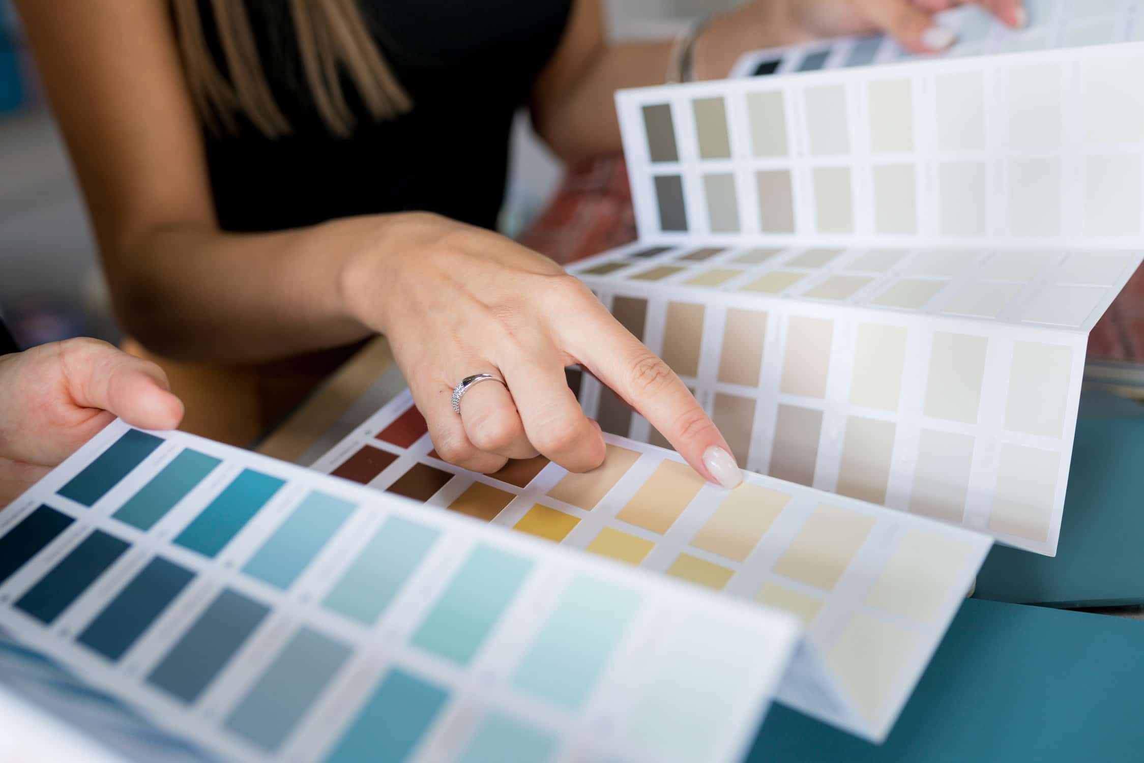 Close-up of two women choosing samples of wall paint.